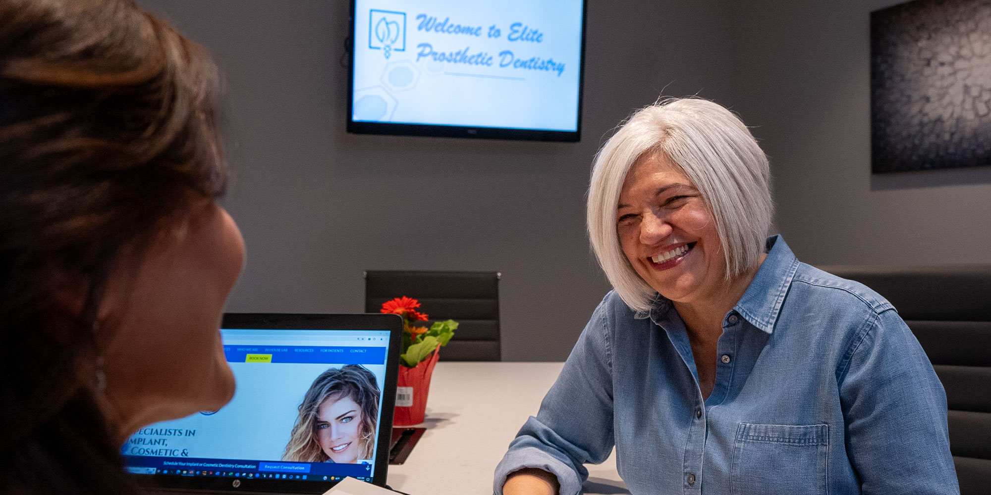Full arch dental implant patient smiling at receptionist at elite prosthetic dentistry in Wahsingtton DC